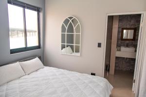 ein weißes Schlafzimmer mit einem Bett und einem Fenster in der Unterkunft Waterfront Apartment in Lüderitz + 19 Fotos