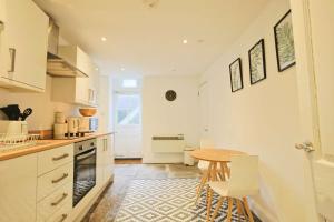 a kitchen with white cabinets and a table and chairs at Spacious Boutique Apartment Clifton King Size Bed in Bristol