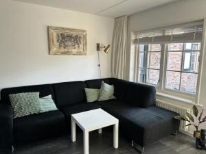 a living room with a black couch and a table at Hello Zeeland - Brouwersbuurt 31 in Domburg