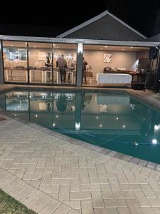 ein Schwimmbad in der Nacht mit einem Hotel im Hintergrund in der Unterkunft Louvre Guesthouse in Bothaville