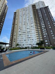 two people in a swimming pool in front of two tall buildings at Cattleya BNB Rentals 1 at Avida Tower 2, CDO in Cagayan de Oro