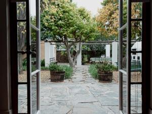 an open door to a courtyard with a tree and benches at Karoo Cypress Guesthouse in Graaff-Reinet +4 photos