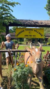 a statue of a man and a cow in a garden at Sauraha Tharu Village in Sauraha