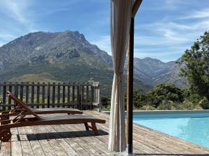 a wooden deck with a bench next to a swimming pool at Dôme avec spa privatif, vue montagne & accès piscine - Domaine l'Aghja Vallica in Vallica