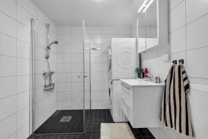 ein weißes Badezimmer mit Waschbecken und Dusche in der Unterkunft Northstay - Cozy Arctic Apartment, Free Parking in Tromsø + 22 Fotos