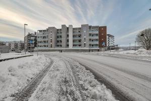 eine leere, schneebedeckte Straße mit einem Gebäude in der Unterkunft Northstay - Cozy Arctic Apartment, Free Parking in Tromsø