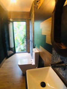a bathroom with a sink and a toilet and a window at Mount shadows in Ella