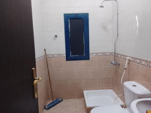 a bathroom with a toilet and a blue window at Alnan room's in Makkah
