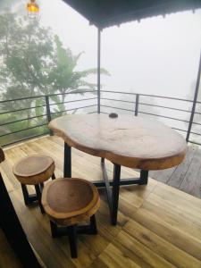 a wooden table and two stools on a balcony at Mount shadows in Ella