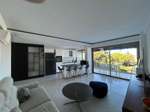 a living room with a couch and a kitchen at Cap d'Antibes Port Aubernon 3P vue Mer Piscine in Antibes