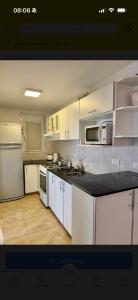 a kitchen with white cabinets and a black counter top at Casa Monte Hermoso Del Este in Monte Hermoso