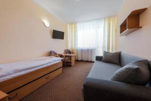 a hotel room with a bed and a couch at Ośrodek Wypoczynkowy Gwarek Ustronie Morskie in Ustronie Morskie