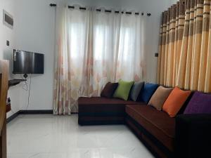 a living room with a brown couch with colorful pillows at Villa Safaya Hikkaduwa in Hikkaduwa