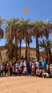 een groep mensen die poseren voor een foto voor palmbomen bij Terregite Taghit in Taghit