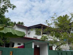 a white house with a fence in front of it at Villa Safaya Hikkaduwa in Hikkaduwa