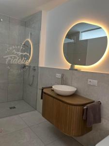 ein Badezimmer mit Waschbecken und Dusche mit Spiegel in der Unterkunft Apartment Fidelia in Sankt Anton im Montafon + 9 Fotos