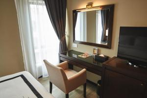 a hotel room with a desk with a mirror and a chair at Corsica Hotel in Kulai