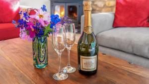 a bottle of wine and two wine glasses on a table at The Stables, Batheaston in Batheaston