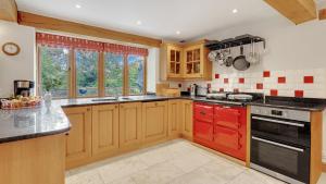 a kitchen with wooden cabinets and a red island in it at The Stables, Batheaston in Batheaston +17 photos