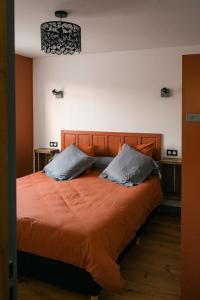 ein Schlafzimmer mit einem großen orangenen Bett mit zwei Kissen in der Unterkunft L'Escale du Cu de Loup in Quettehou