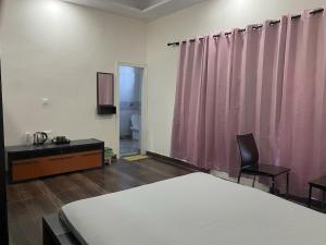 a bedroom with a bed and a pink curtain at The Nest spacious and homely flat in Haldwani in Haldwāni