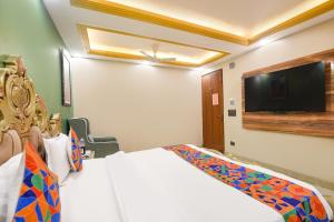 大诺伊达FabHotel Elegant Stay的一间卧室，里面有一张床和一台平板电视