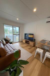 a living room with a couch and a tv at Renovated 3-Bedroom Beach House Sunshine Coast in Golden Beach