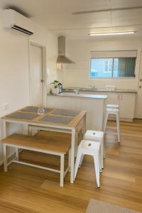 a kitchen with a table and two white stools at Renovated 3-Bedroom Beach House Sunshine Coast in Golden Beach