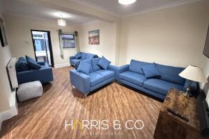 a living room with blue couches and a television at Sandringham & Spa Villa in Thornton