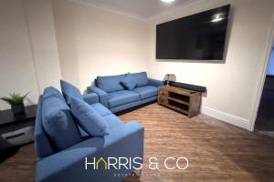 ein Wohnzimmer mit einem blauen Sofa und einem Flachbild-TV in der Unterkunft Sandringham & Spa Villa in Thornton