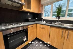 eine Küche mit Holzschränken, einem Herd und einer Spüle in der Unterkunft Sandringham & Spa Villa in Thornton + 27 Fotos