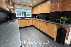 eine große Küche mit Holzschränken und einem Waschbecken in der Unterkunft Sandringham & Spa Villa in Thornton