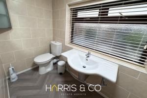 un bagno con un water, un lavandino e una finestra di Sandringham & Spa Villa a Thornton