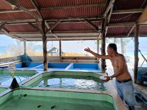 a man standing in a pool of water with a frisbee at Meno Turtle BUNGALOWS in Gili Meno