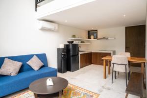Una sala de estar con un sofá azul y una cocina. en SUNSET-LOFT Seminyak, en Seminyak