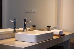 Un mostrador de baño con un lavabo blanco y espejos. en SUNSET-LOFT Seminyak, en Seminyak 7 fotos más