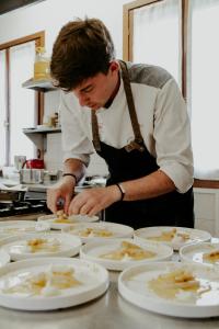 a man in a kitchen preparing food on white plates at Ghisolana Agriturismo al Capitello in Asolo