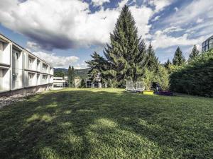 a large yard with a large tree and a building at Mercure Annecy Sud in Annecy