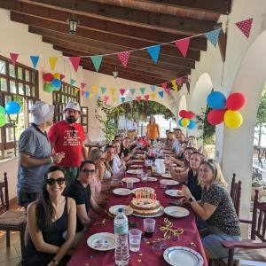 un gruppo di persone sedute a un lungo tavolo con una torta di compleanno di Villa La Gran Duquesa a Playa de San Juan
