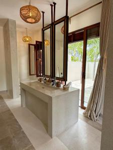 une salle de bain avec un lavabo et un grand miroir dans l'établissement Maya kobe Beachfront Retreat Kilifi, à Kilifi
