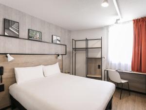 Una habitación de hotel con una cama blanca y un escritorio. en ibis Avignon Sud, en Aviñón