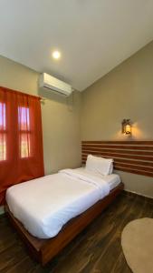 a bedroom with a large bed with white sheets and a window at Sauraha Tharu Village in Sauraha