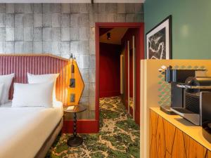 ein Hotelzimmer mit einem Bett und einem Fernseher in der Unterkunft Hotel Maison Louise Lille Centre - Handwritten Collection in Lille