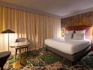 ein Hotelzimmer mit einem großen Bett und einem Tisch in der Unterkunft Hotel Maison Louise Lille Centre - Handwritten Collection in Lille + 132 Fotos
