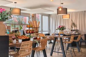 a dining room with tables and chairs with food on them at The Originals City, Le Beaujoire, Nantes - En face du Parc des Expositions et face au Stade Beaujoire in Nantes
