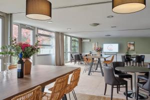 un restaurant avec des tables et des chaises et un bar dans l'établissement The Originals City, Le Beaujoire, Nantes - En face du Parc des Expositions et face au Stade Beaujoire, à Nantes