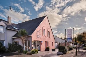 un bâtiment rose avec un toit noir dans une rue dans l'établissement The Originals City, Le Beaujoire, Nantes - En face du Parc des Expositions et face au Stade Beaujoire, à Nantes