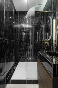 a bathroom with black tiled walls and a shower at PoeticStay - Neuilly in Neuilly-sur-Seine