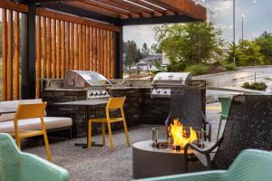 a patio with a fire pit and chairs and a grill at Home2 Suites By Hilton Woodstock On in Woodstock