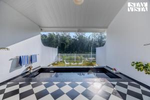 una piscina en una casa con suelo a cuadros en StayVista at Mudra Tattva - Pvt Pool,Lawn,Jacuzzi 2BR Luxury Rooms, en Suntikoppa